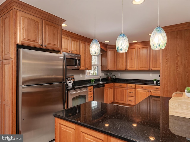 kitchen featuring stainless steel appliances, sink, dark stone counters, and decorative light fixtures