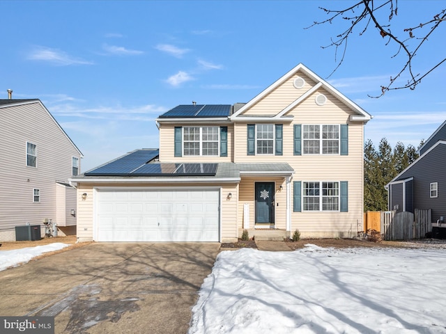 view of front of home with a garage, central AC unit, and solar panels