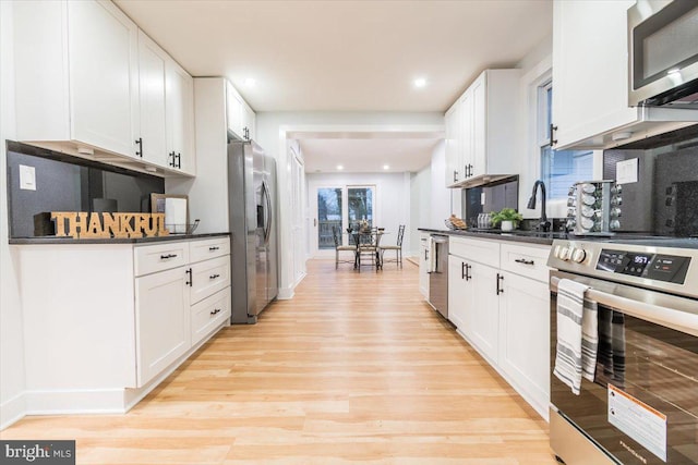 kitchen featuring white cabinets, light wood-type flooring, and stainless steel appliances