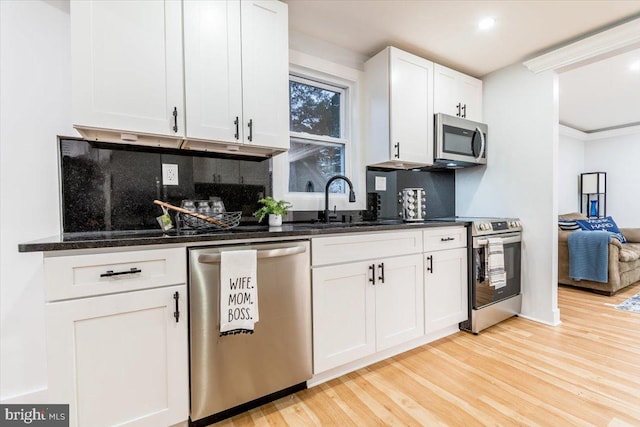 kitchen featuring white cabinets, decorative backsplash, light wood-type flooring, and stainless steel appliances