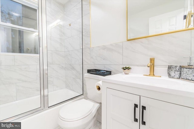 full bathroom featuring tasteful backsplash, bath / shower combo with glass door, toilet, vanity, and tile walls