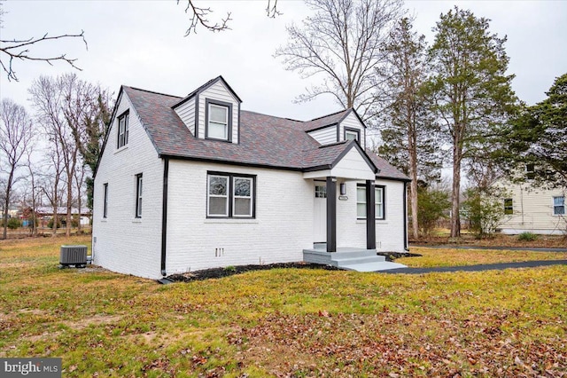 cape cod home with central AC unit and a front lawn