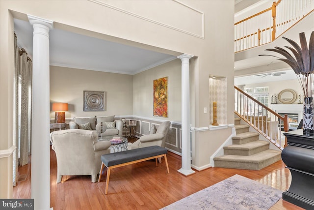 living room featuring ornate columns, crown molding, ceiling fan, and wood-type flooring