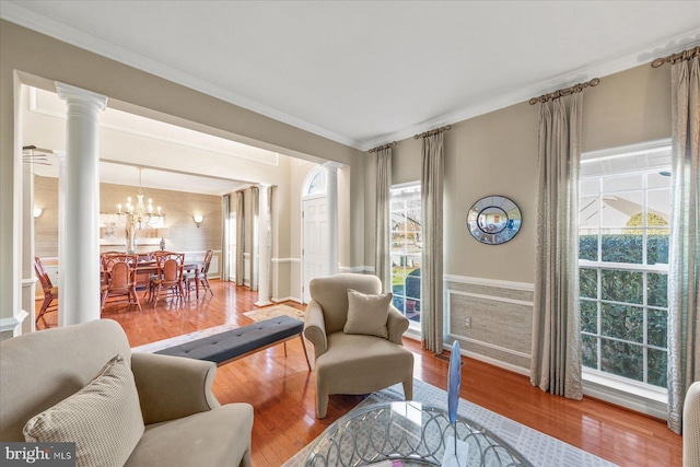 interior space with ornate columns, a healthy amount of sunlight, crown molding, hardwood / wood-style flooring, and a chandelier