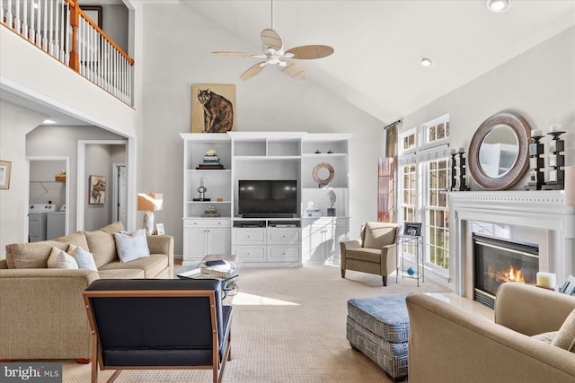 carpeted living room with high vaulted ceiling, a healthy amount of sunlight, washing machine and dryer, and a high end fireplace