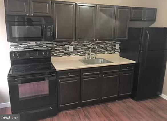 kitchen featuring dark hardwood / wood-style flooring, sink, backsplash, and black appliances