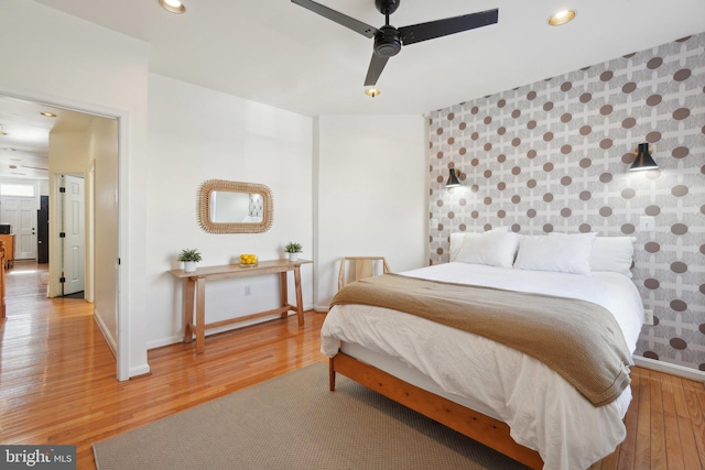 bedroom with baseboards, an accent wall, wood finished floors, and recessed lighting