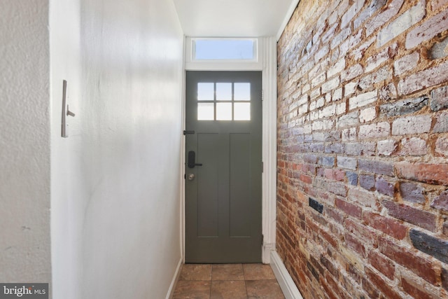 doorway to outside with brick wall and baseboards