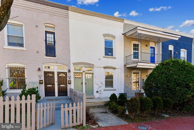townhome / multi-family property with brick siding and a fenced front yard