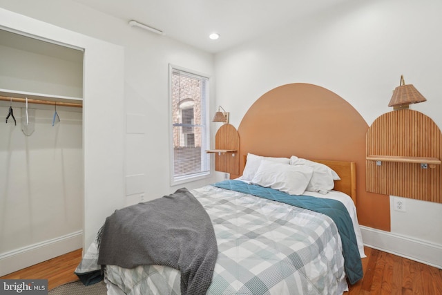 bedroom with a closet, baseboards, wood finished floors, and recessed lighting