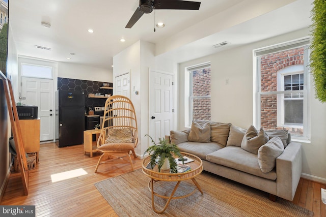 living area featuring recessed lighting, a ceiling fan, baseboards, visible vents, and light wood finished floors