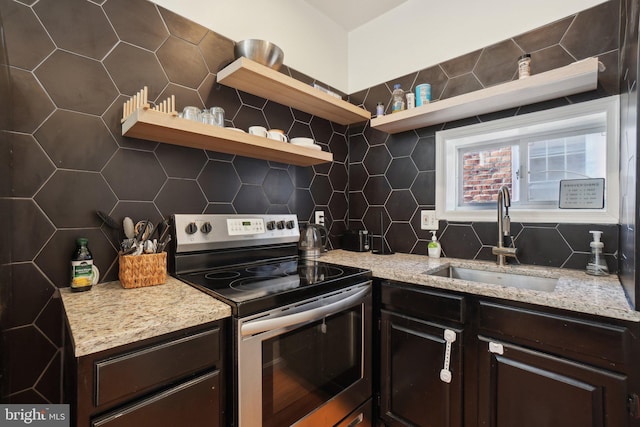 kitchen with stainless steel electric range oven, a sink, dark brown cabinets, open shelves, and backsplash