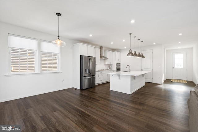 kitchen with sink, pendant lighting, a kitchen bar, a kitchen island with sink, and appliances with stainless steel finishes