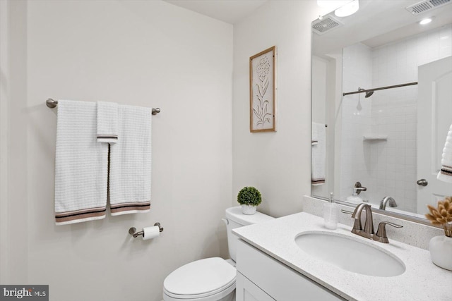 bathroom featuring a tile shower, vanity, and toilet