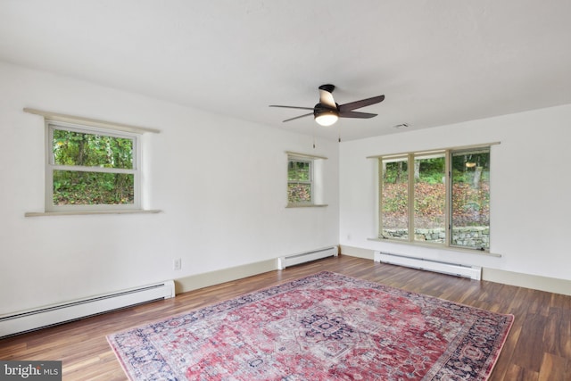 unfurnished room featuring a healthy amount of sunlight, hardwood / wood-style flooring, and a baseboard heating unit