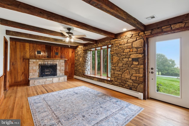 unfurnished living room with beamed ceiling, a wealth of natural light, light hardwood / wood-style floors, and baseboard heating