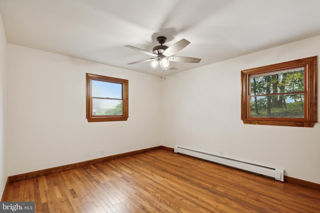 spare room with hardwood / wood-style flooring, ceiling fan, and a baseboard heating unit