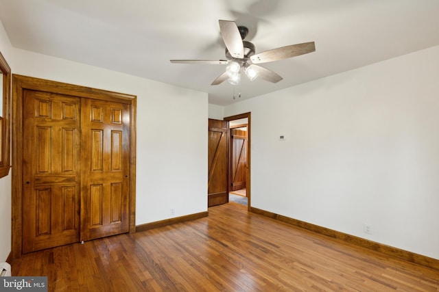 unfurnished bedroom featuring hardwood / wood-style floors, ceiling fan, and a baseboard heating unit