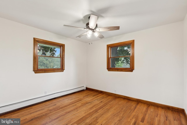 unfurnished room with light wood-type flooring, a wealth of natural light, and a baseboard heating unit