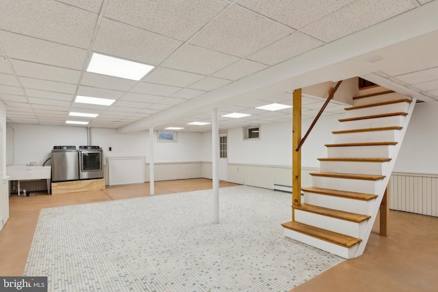 basement with a paneled ceiling, washing machine and dryer, sink, and a baseboard heating unit