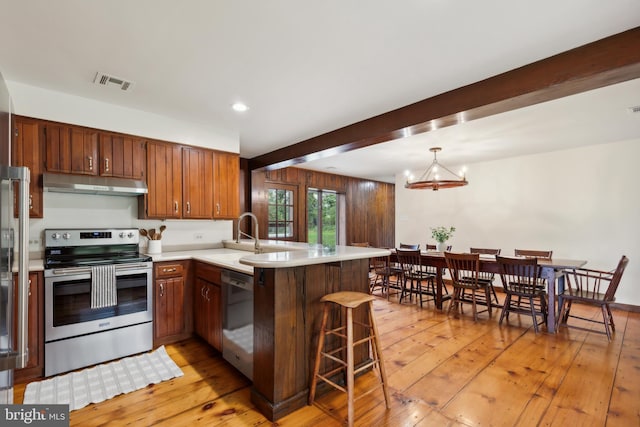 kitchen with kitchen peninsula, light hardwood / wood-style flooring, beamed ceiling, and stainless steel appliances