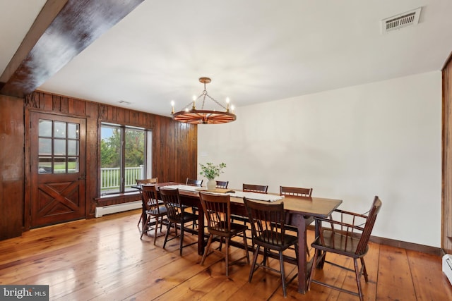 dining space featuring wooden walls, beamed ceiling, light hardwood / wood-style floors, and a notable chandelier