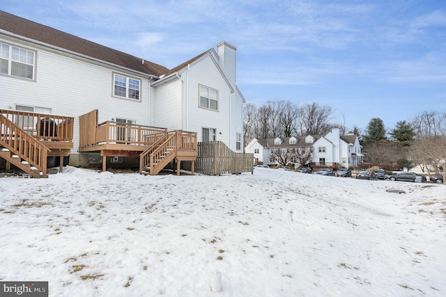 snow covered rear of property with a deck