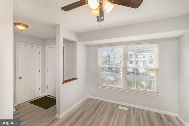 spare room with ceiling fan, light hardwood / wood-style floors, and a textured ceiling