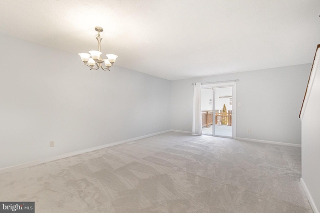 carpeted spare room featuring a chandelier