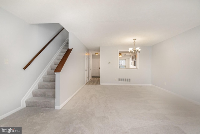 carpeted empty room featuring an inviting chandelier