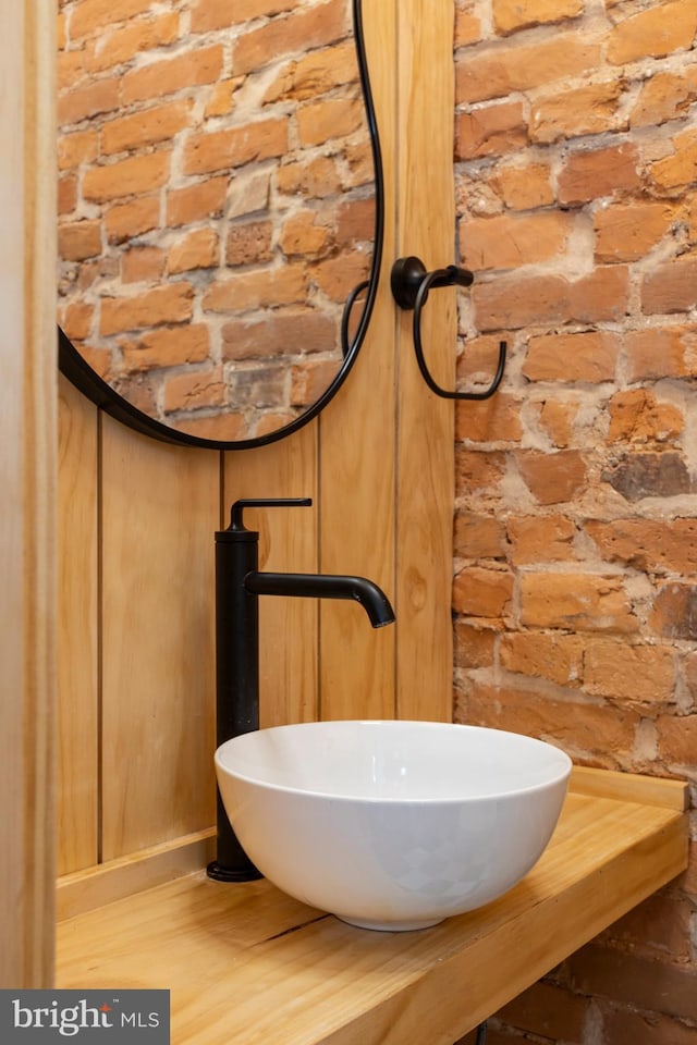 bathroom featuring sink, brick wall, and wood-type flooring