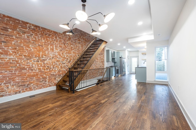 unfurnished living room featuring crown molding, brick wall, and dark hardwood / wood-style floors