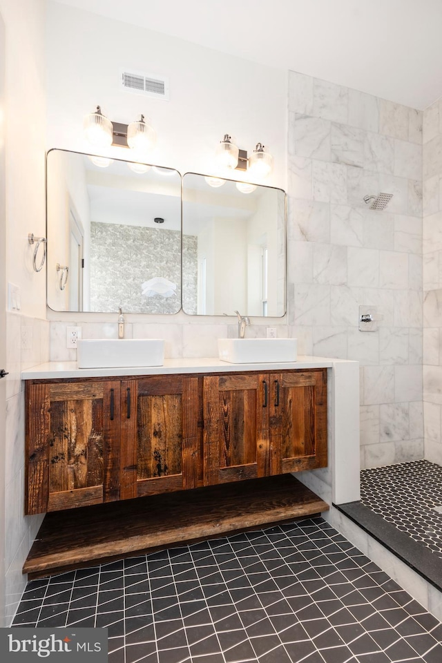 bathroom featuring tile patterned flooring, a tile shower, vanity, and tile walls