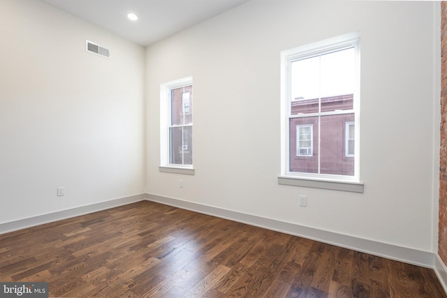 spare room featuring dark hardwood / wood-style floors and a healthy amount of sunlight