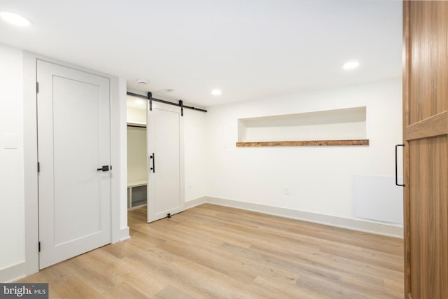 unfurnished room featuring a barn door and light wood-type flooring