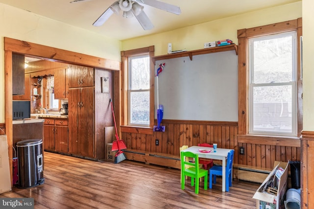 playroom with ceiling fan, hardwood / wood-style flooring, a wealth of natural light, and wood walls