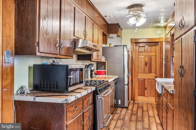 kitchen featuring light wood-type flooring, stainless steel appliances, and ceiling fan