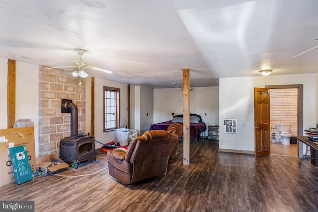 living room featuring ceiling fan, dark hardwood / wood-style flooring, and a wood stove