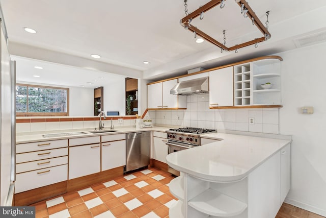 kitchen featuring kitchen peninsula, tasteful backsplash, wall chimney exhaust hood, stainless steel appliances, and white cabinets