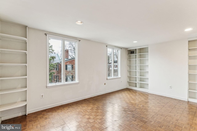 spare room with built in features and light parquet floors