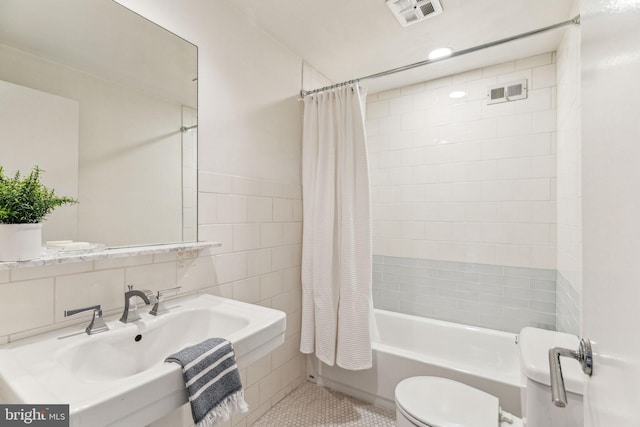 full bathroom featuring tile patterned floors, sink, toilet, tile walls, and shower / tub combo