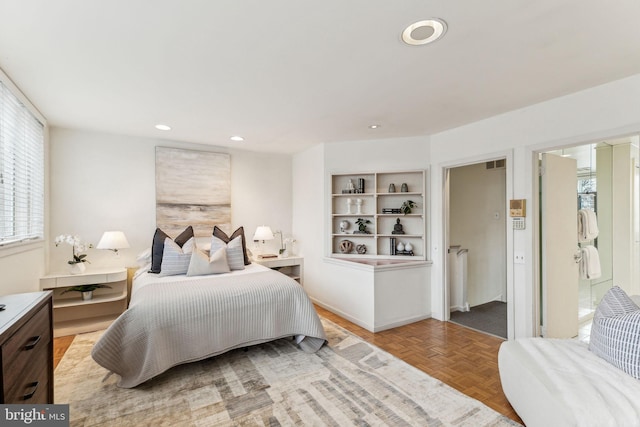 bedroom with connected bathroom and light parquet floors