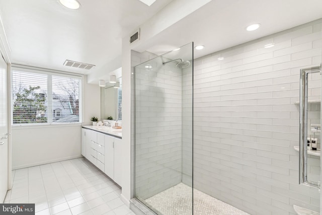 bathroom with tiled shower, vanity, and tile patterned floors