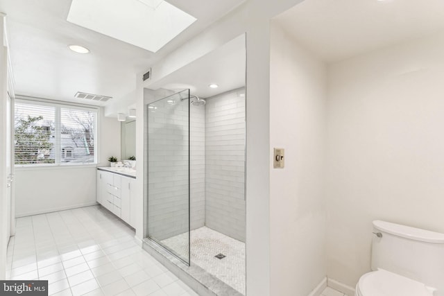 bathroom featuring vanity, a skylight, tile patterned flooring, toilet, and tiled shower