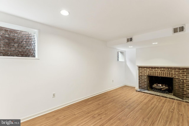 unfurnished living room featuring hardwood / wood-style flooring and a brick fireplace