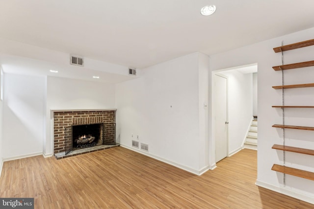 unfurnished living room featuring light hardwood / wood-style floors and a brick fireplace