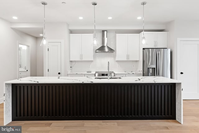 kitchen featuring stainless steel fridge with ice dispenser, white cabinetry, wall chimney exhaust hood, and a spacious island