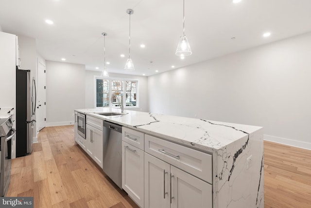 kitchen featuring white cabinets, sink, stainless steel appliances, and a center island with sink