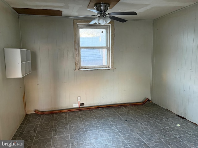 unfurnished room featuring ceiling fan and wood walls