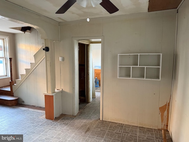 empty room featuring ceiling fan and wood walls